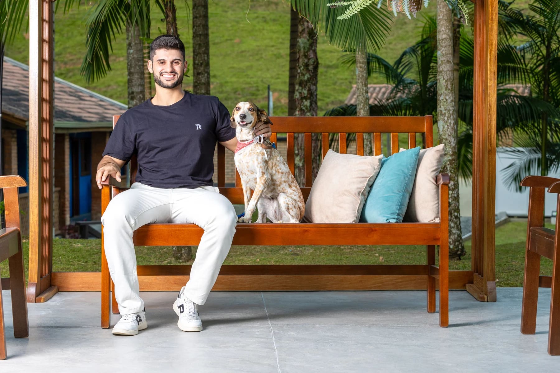 Pessoa e cachorro sentados em um banco de madeira da Móveis Daniella no jardim